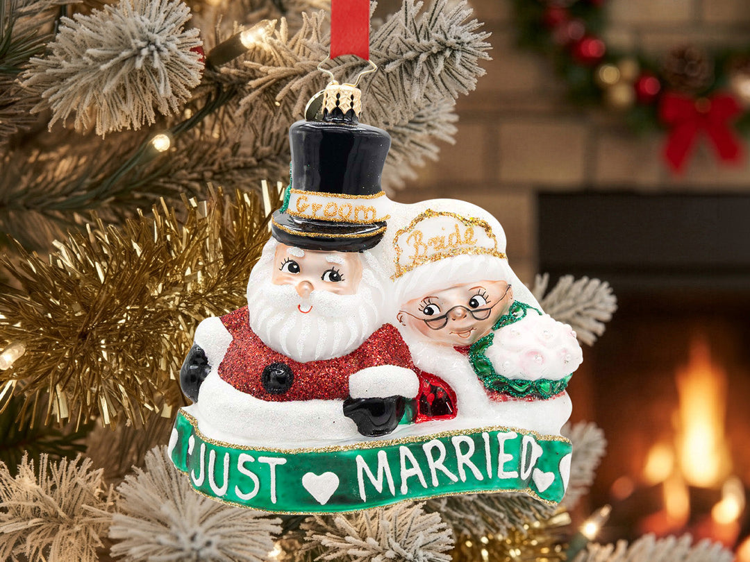 An ornament with a pair of white wedding birds nestled together with pink flowers and the year 2025 marked below on a blue ribbon.