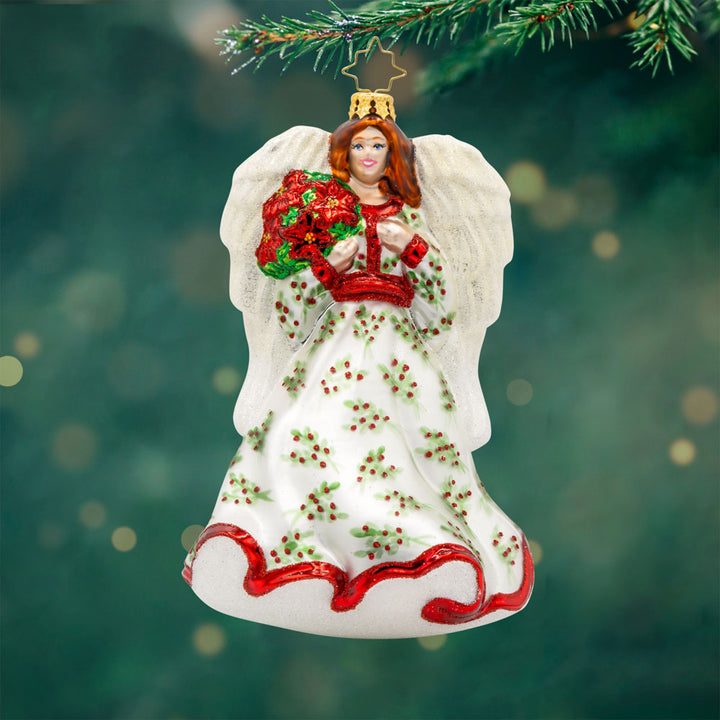 Angelic Poinsettia Herald ornament. Features an angel wearing a flowing hand-painted gown holding a poinsettia bouquet. View of front.