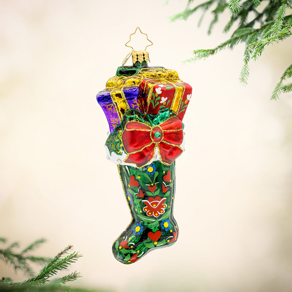 Folklore Charm ornament. This emerald, green stocking is adorned with intricate folk art designs, vibrant colors, and gifts coming out the top. View of front. 