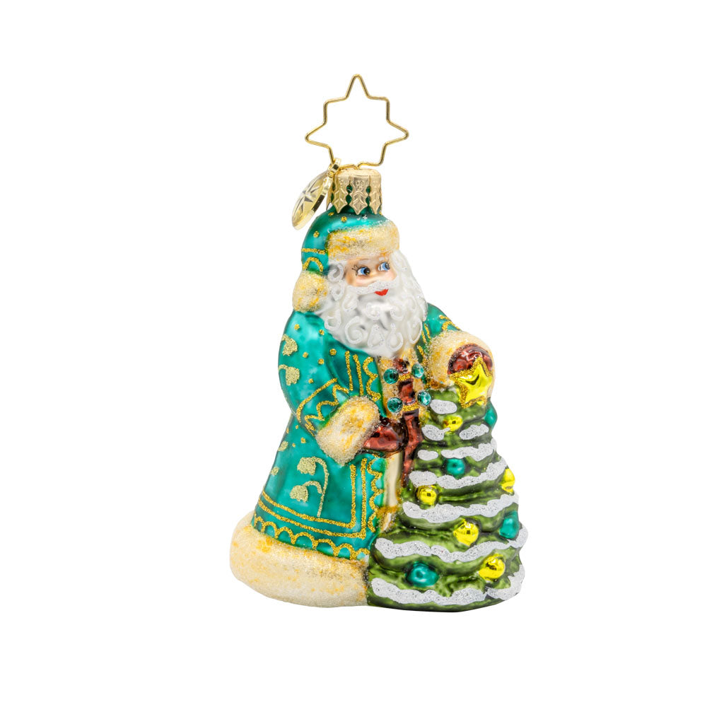 Santa's Tinsel Touch Gem ornament. Santa dons a green and gold intricately detailed robe as he tends to a tiny Christmas tree. View of front. 