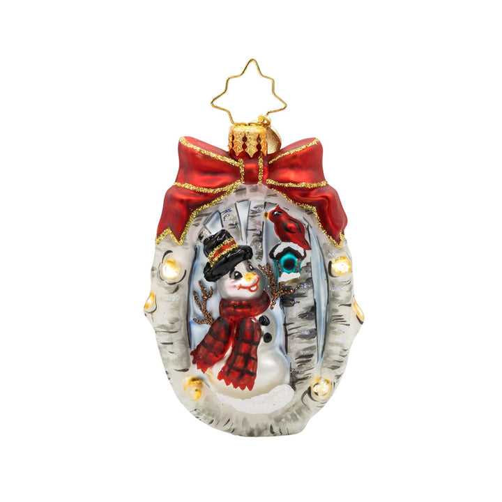 A Snowy Feathered Friend Gem ornament. A snowman and a cardinal in its birdhouse, are encircled by a wreath made of birch branches with a red bow on top. View of front. 