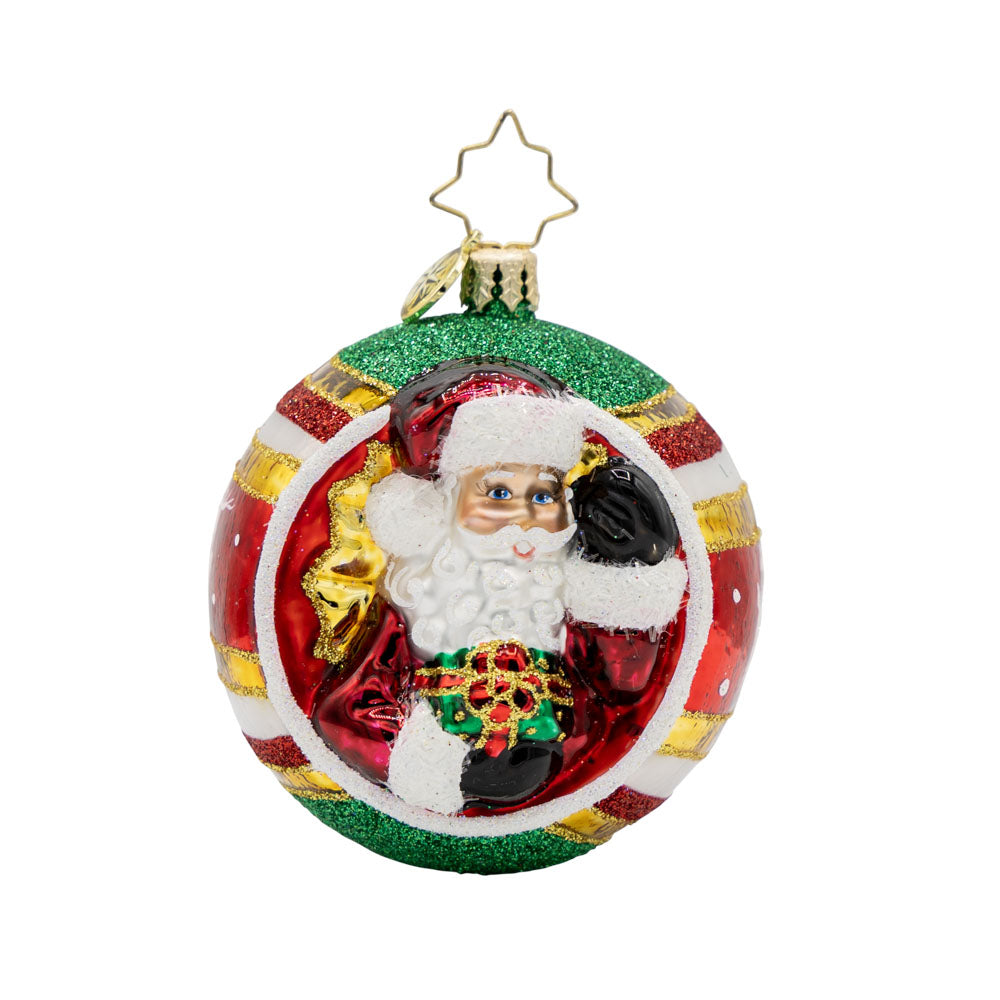 St. Nick's Spherical Cheer Gem ornament. On this ornament round of striped, red, green, and gold, Santa is seen carrying a gift. View of front. 
