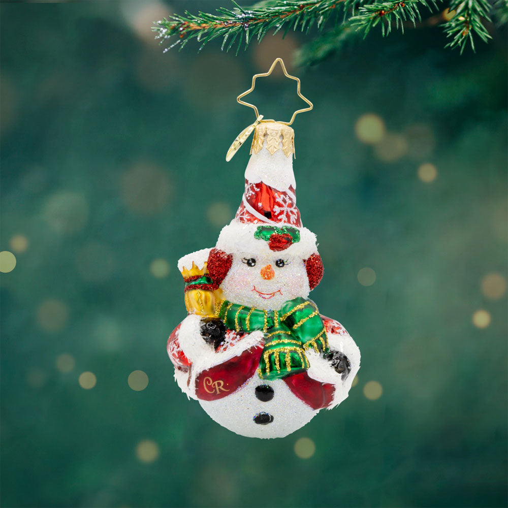 Swept Up Snowman Gem ornament. A snowman donned in a red and snowflake flecked coat with a broom in hand. View of front.  