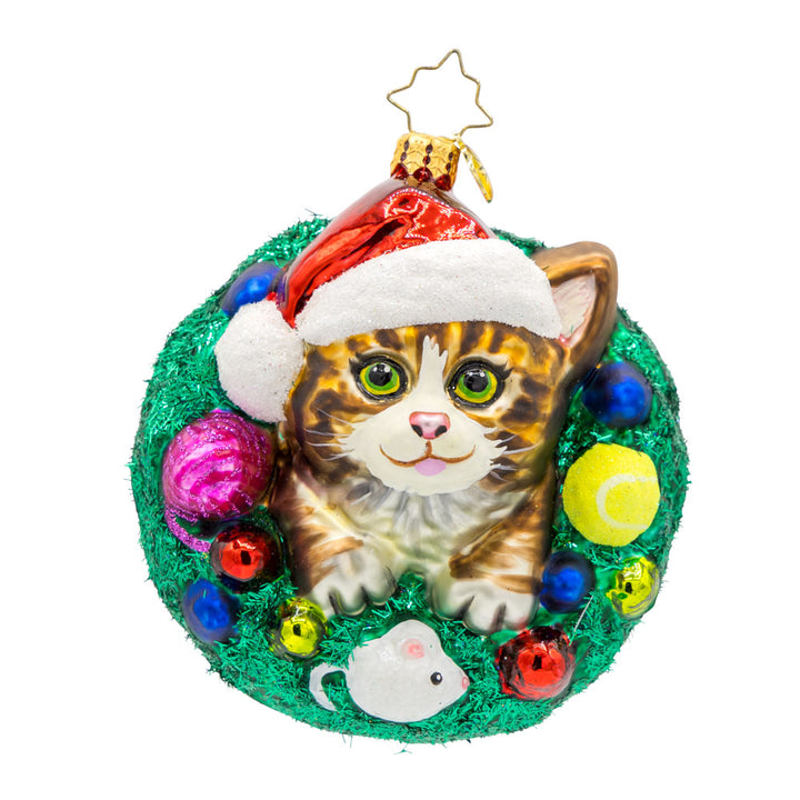 Merry Catmas ornament. Features a cat wearing a Santa hat, encircled by a wreath and toys. View of front. 