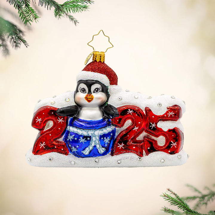 Frosty Flipper Countdown ornament. A penguin pops out of a blue gift bag, making up the zero in "2025." View of front.