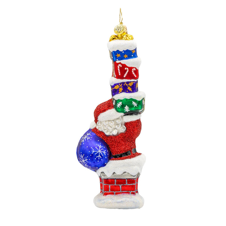 Kris Kringle's Chimney Trek 2025 ornament. Santa is coming out of a chimney, gift sack in hand and a stack of gifts dated "2025." in the other. View of back.