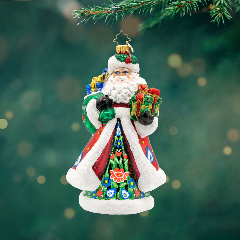 Folk Festive Claus ornament. Clad in a sumptuous dark green gown, adorned with a hand-painted folk pattern, this Santa celebrates the beauty of Polish heritage. View of front. 