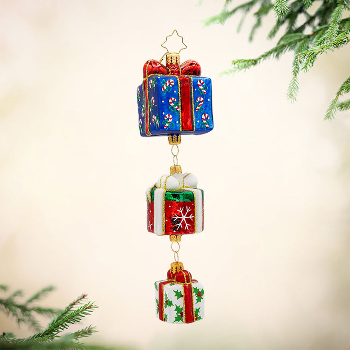 Holiday Haul ornament. This charming piece features three beautifully wrapped presents, each with a unique design and color. View of front.