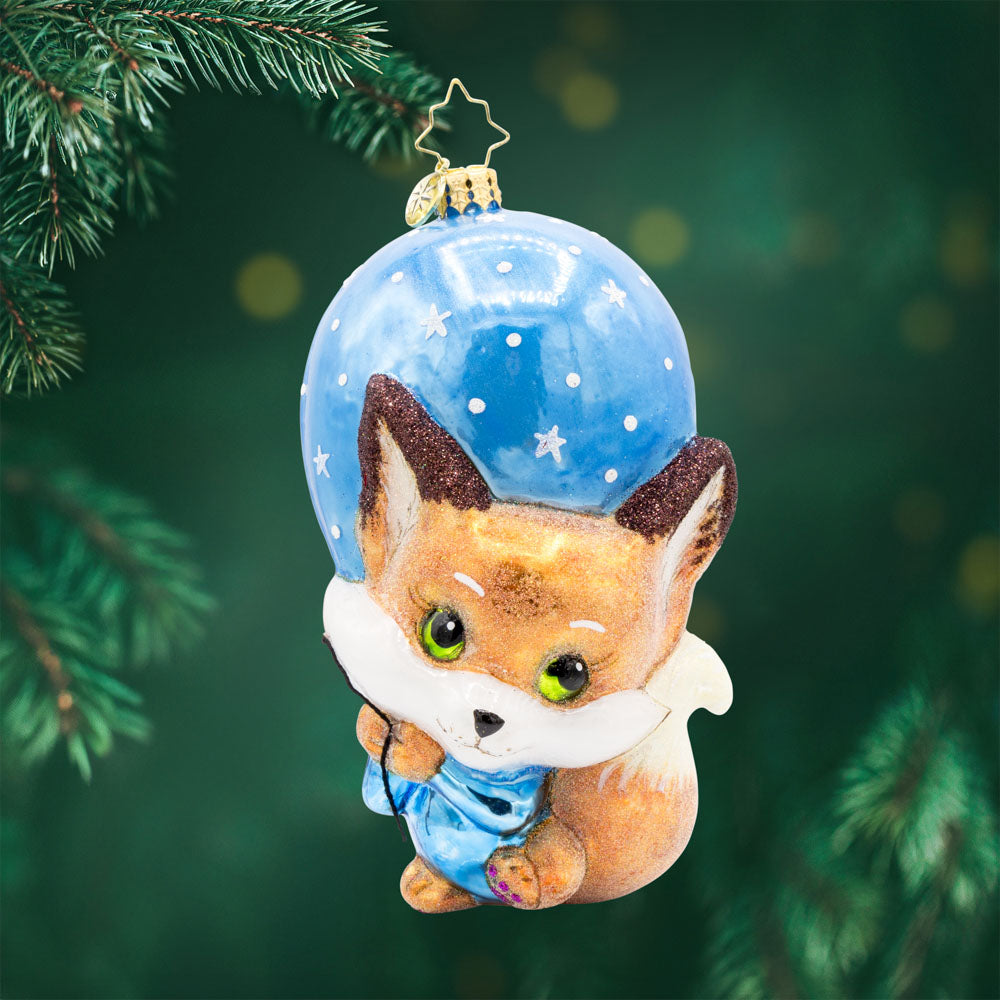 Blue Foxy Float ornament. Featuring a baby fox holding onto a blue balloon. View of front. 
