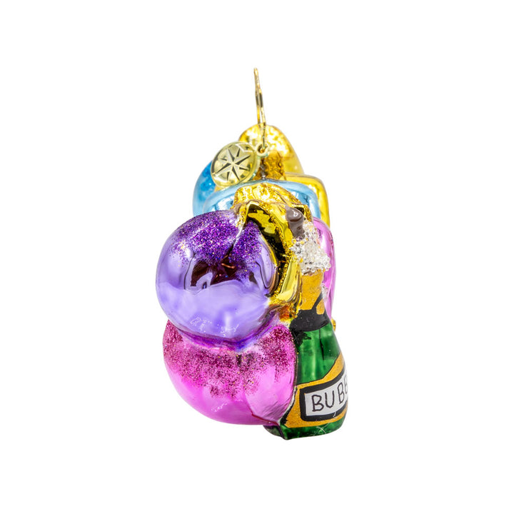 Cheers to 2026 ornament. "2026" shaped ballons in festive colors of pink, gold, blue and purple. Accompanied with a bottle of bubbles and flute glasses. View of left side.