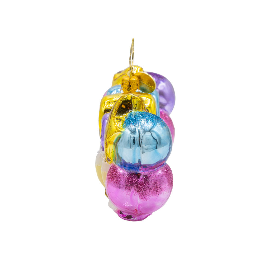 Cheers to 2026 ornament. "2026" shaped ballons in festive colors of pink, gold, blue and purple. Accompanied with a bottle of bubbles and flute glasses. View of right side.