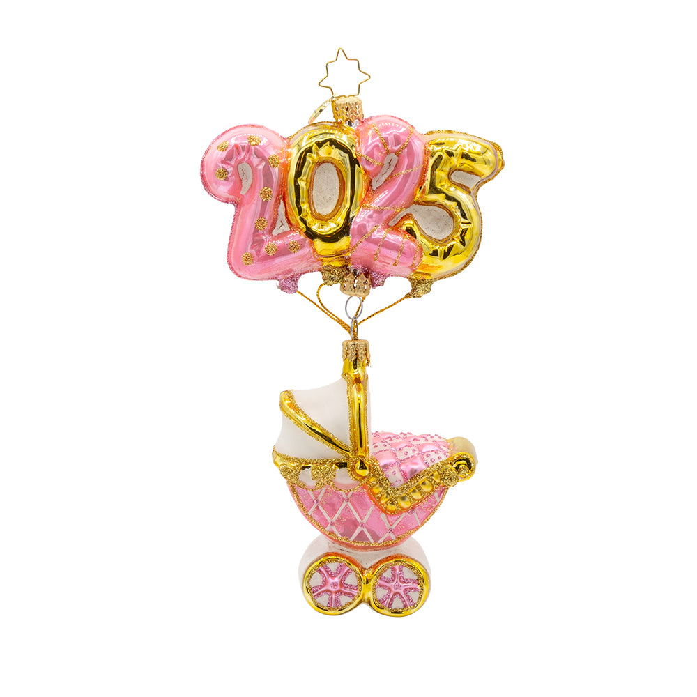Baby Pink Cradle of Celebration ornament. Features a decorated baby pink carriage and "2025" shaped balloons. View of front. 