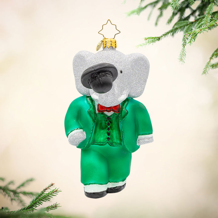King Babar ornament. Babar dons his green suit, holding a top hat with his trunk. View of front. 