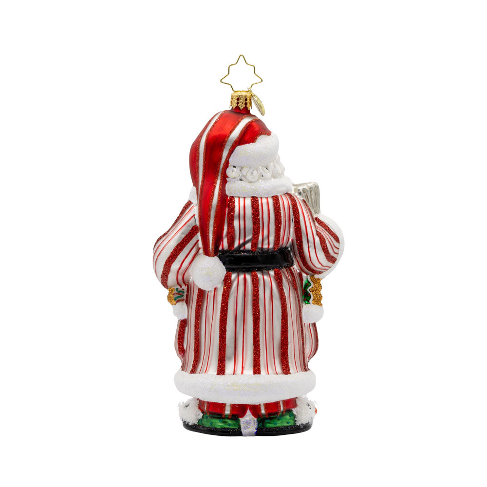 Santa's Daily News ornament. Santa is wearing a striped robe, snowman slippers, with mug of hot cocoa in hand. In the other hand he reads the newspaper. View of back.