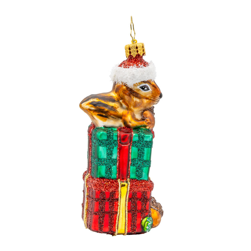 Chipper Cheer ornament. A chipmunk sits atop a stack of gifts with an acorn in hand. View of left side.