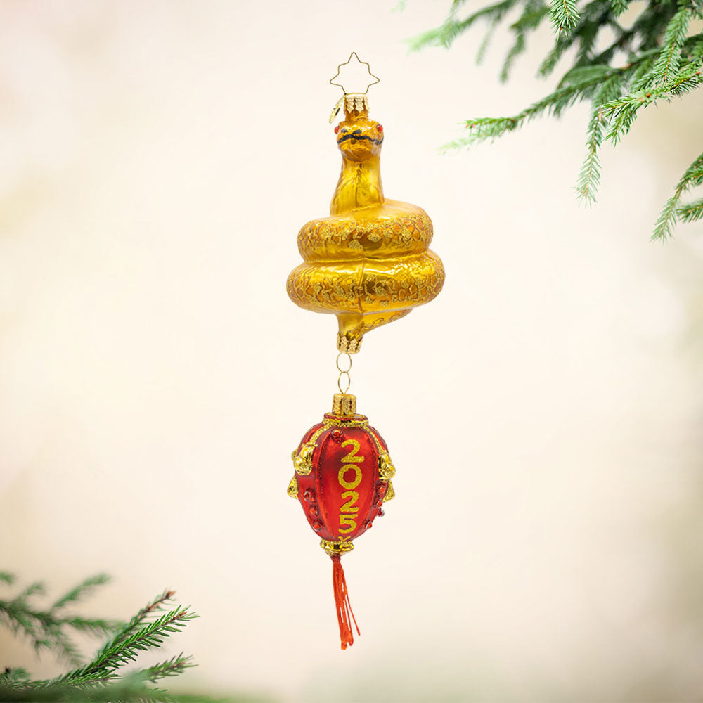 2025 Year of the Snake ornament. A red lantern dangles from a coiled gold snake, adorned with shimmering red accents View of front. 