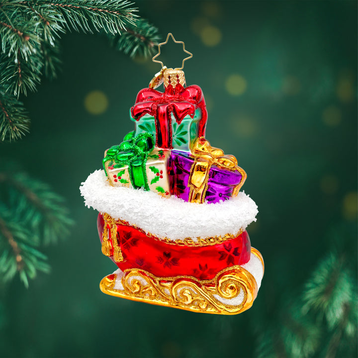 Sleighful of Wonders ornament. A bright red and gold sleigh is overflowing with gifts. View of front. 
