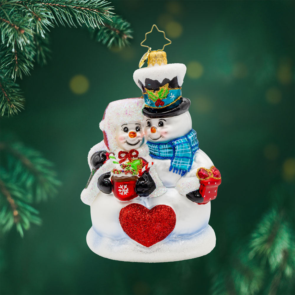Winter Lovebirds ornament. A lady and gentleman snowman cuddle up with a cup of hot cocoa. View of front. 