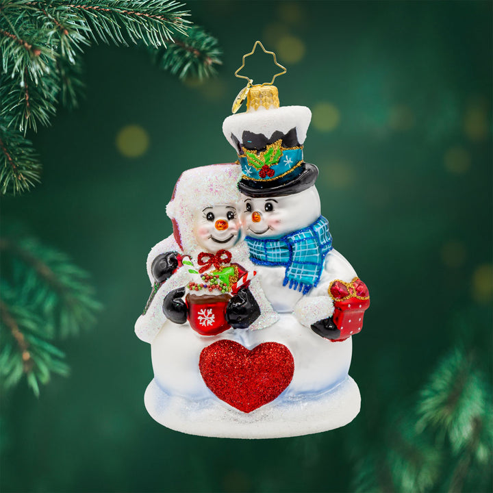 Winter Lovebirds ornament. A lady and gentleman snowman cuddle up with a cup of hot cocoa. View of front. 