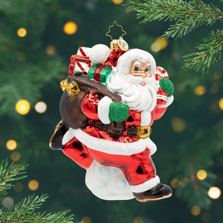 Hustlin' Through the Holidays. Ornament of Santa walking in his red suit while carrying a brown bag full of presents. View of front.