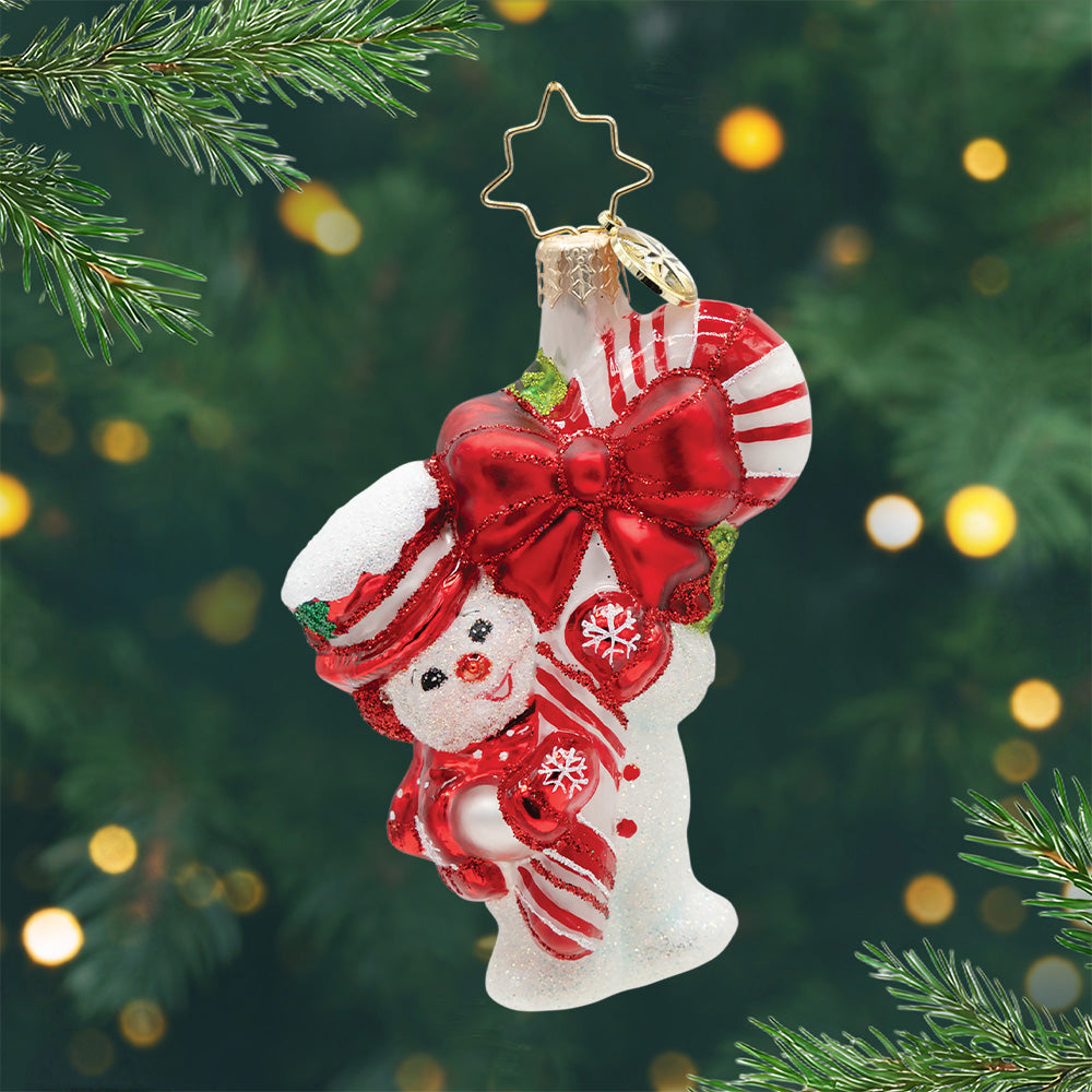 Snowy Retro Cheer Gem. Snowman ornament holding a red and white striped candy cane with a giant red bow and dressed in a matching red hat, scarf and gloves. View of front