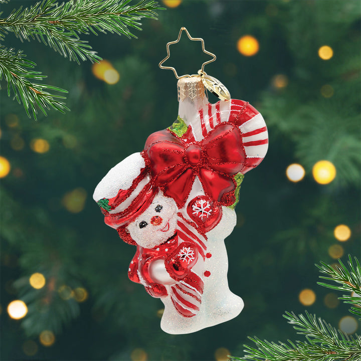 Snowy Retro Cheer Gem. Snowman ornament holding a red and white striped candy cane with a giant red bow and dressed in a matching red hat, scarf and gloves. View of front