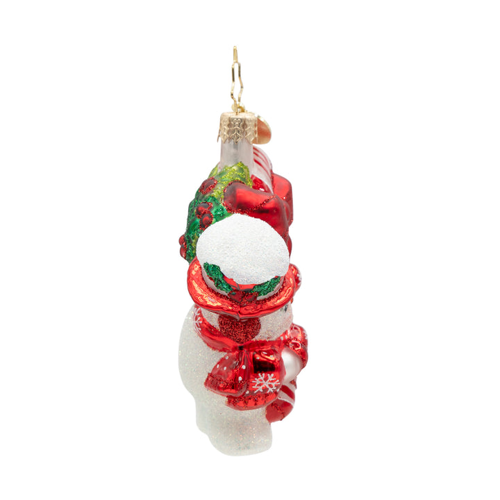 Side of a snowman ornament of a candy cane held by a white snowman with red gloves and red hat covered snow on a white background