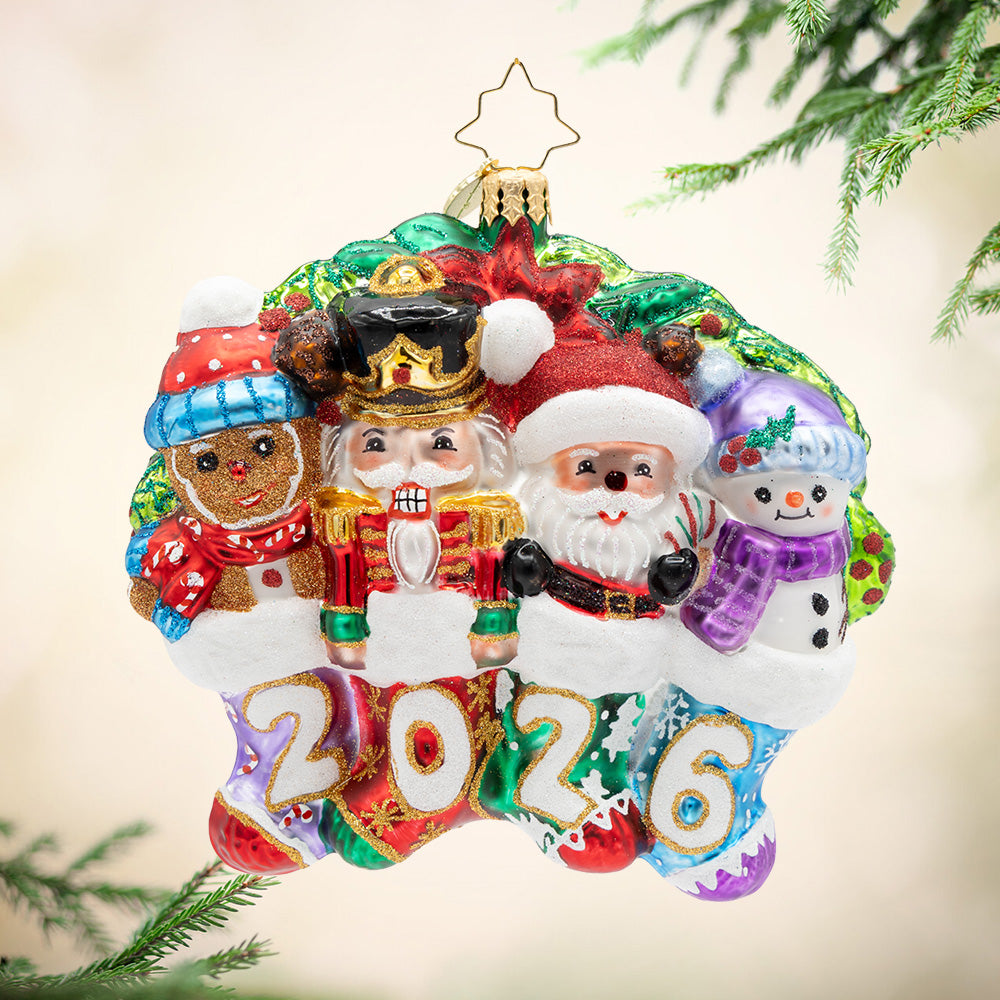 2026 Together for the Holidays. A vibrant ornament of a gingerbread man, a nutcracker, Santa, and a snowman, all inside different stockings that spell 2026. View of front
