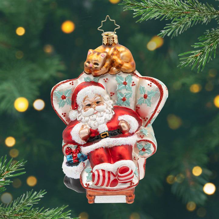 Cat Nap Santa. Ornament of Santa napping in a giant white hare with mistle toes and a bright orange cat on top.