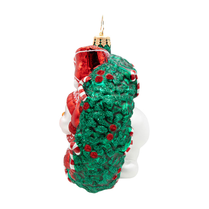 Side of a decorative Christmas ornament shaped like a green wreath with red berries on the side on a white background