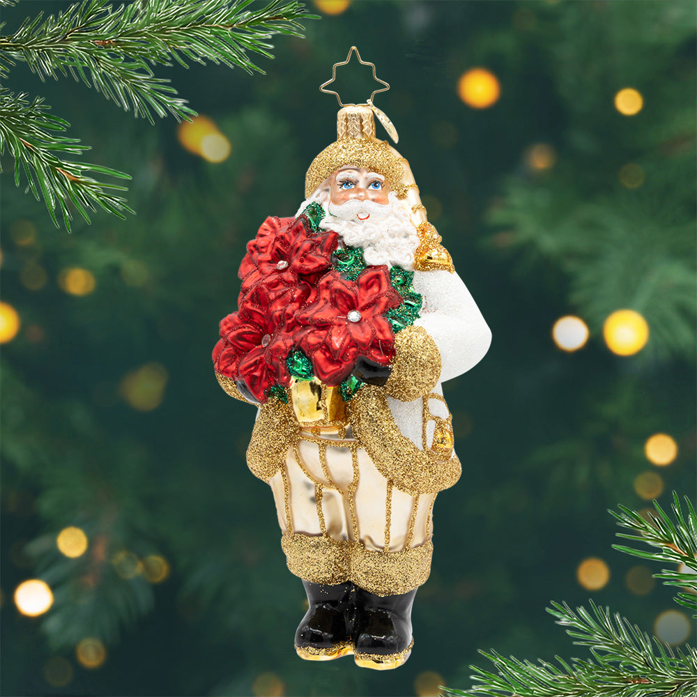 Santa’s Holiday Bloom. This ornament of Santa dressed in a sparkling white and gold suit, while holding a bouquet of bright red poinsettias, will bring festive flair to your tree. View of front.