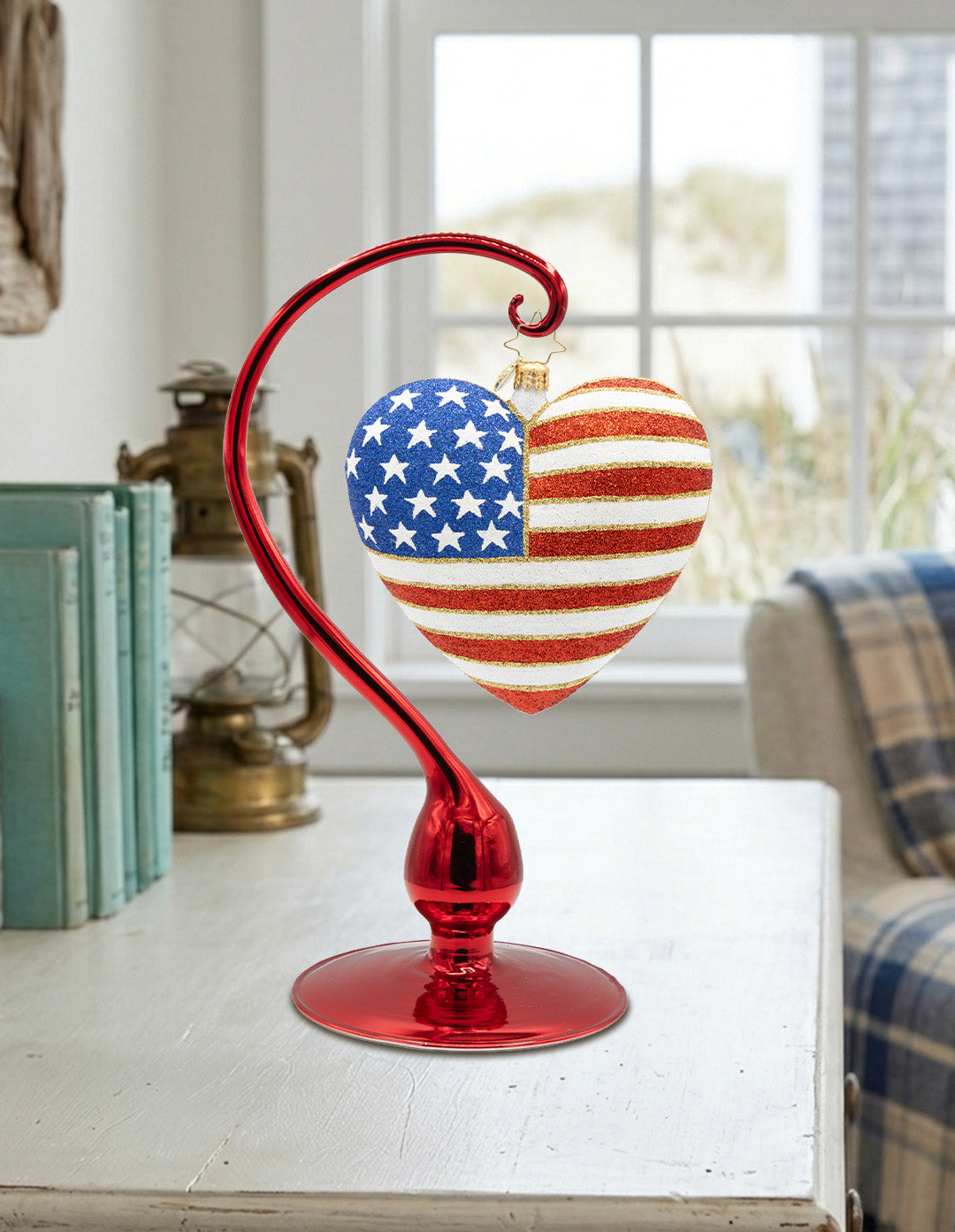 American flag heart ornament hanging on red glass ornament stand