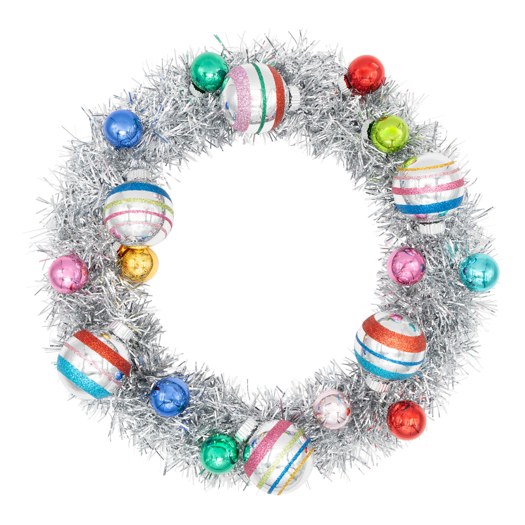 CHRISTMAS CONFETTI SILVER TINSEL WREATH WITH 1" AND 1.75" ROUNDS. Silver tinsel wreath with small red, pink, blue, teal, and green ornaments and some bigger ornament in silver with colored stripes.