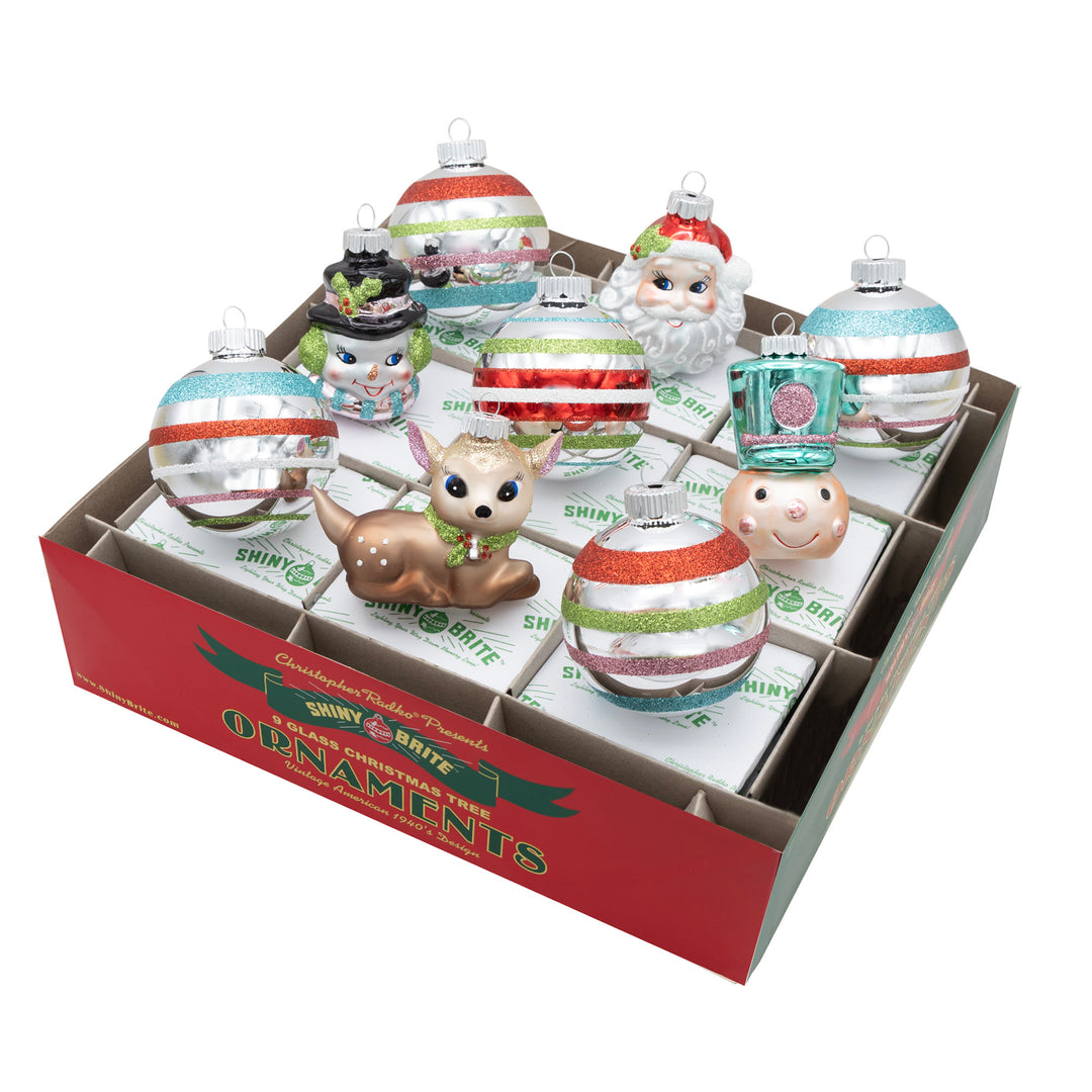 FESTIVE FETE 9 COUNT 2.5" DECORATED ROUNDS & FIGURES. Five silvers round ornaments with colored stripes of red, green, pink, and teal, along with 4 other ornaments in the shapes of a deer, and heads of a snowman head, Santa, and a nutcracker