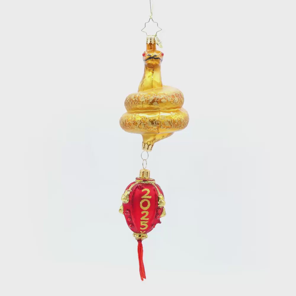 2025 Year of the Snake ornament. A red lantern dangles from a coiled gold snake, adorned with shimmering red accents Video.