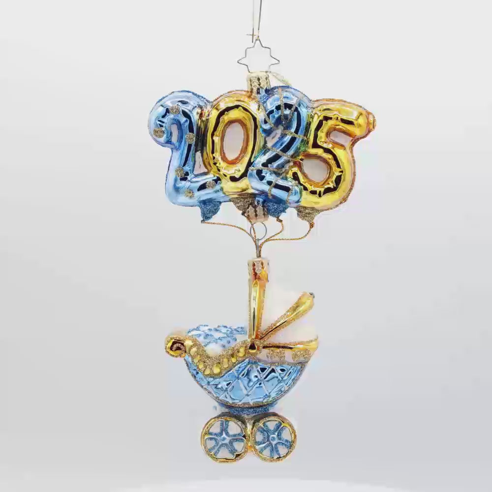 Baby Blue Cradle of Celebration ornament. Features a decorated baby blue carriage and "2025" shaped balloons. Video.