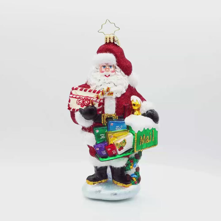 North Pole Mail Delivery ornament. Santa dons his red suit, standing next to a green mailbox filled with letters. Video.