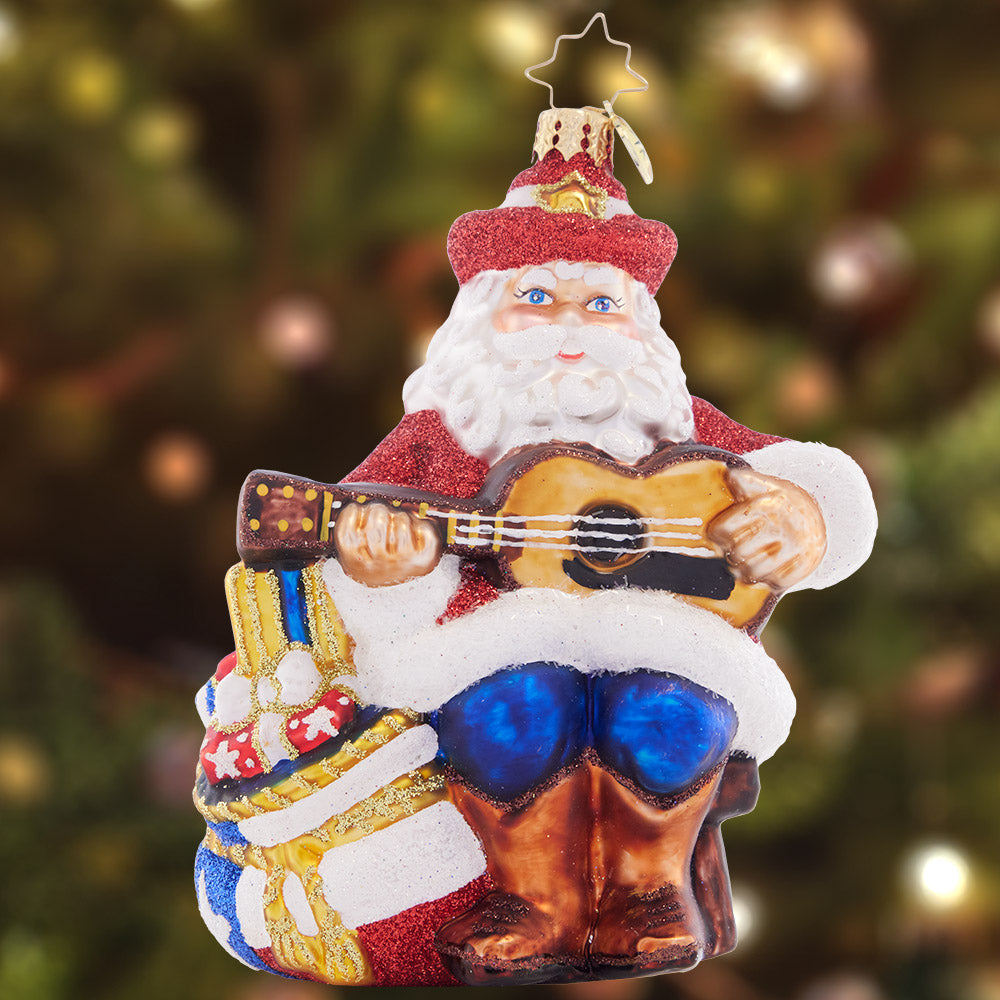 Ornament Description - Lone Star Seranade Santa: Lone star santa strums his four-string, showing his Texas pride with a star-spangled bag of Christmas gifts at his side.