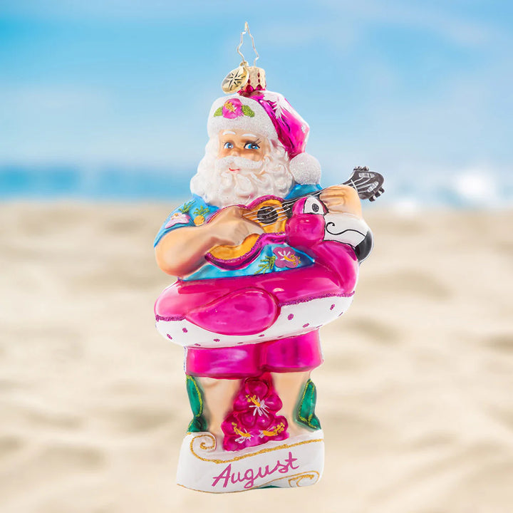 Ornament Description - Beating the Heat: Santa is soaking up some summer sun, giving his ukulele a sound strum. As the eighth piece in our Ornament of the Month collection, he is here to savor summer.